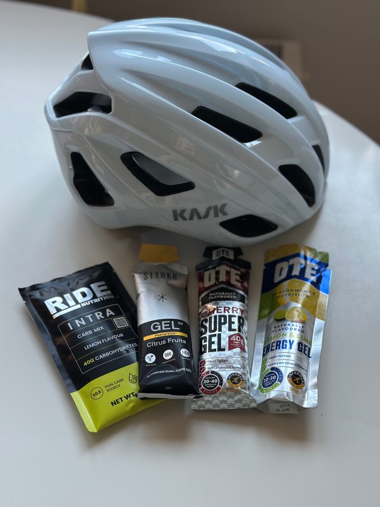 A white cycling helmet with four energy drinks arranged on a table.